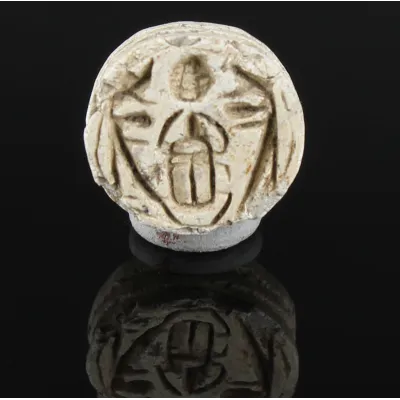 Obverse, for Egyptian — Button seal with protective uraei or Horus falcons flanking kheper beetle, holding rising sun — New...