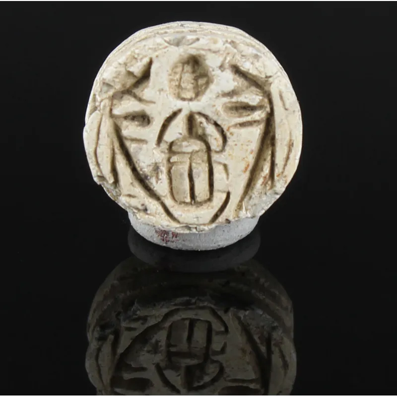 Obverse, for Egyptian — Button seal with protective uraei or Horus falcons flanking kheper beetle, holding rising sun — New...